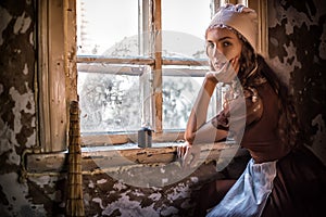 Sad woman in a rustic dress sitting near window in old house feel lonely. Cinderella style