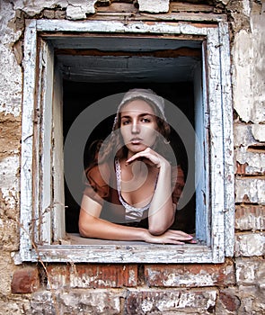 Sad woman in a rustic dress sitting near window in old house feel lonely. Cinderella style