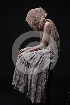Sad woman in scarf sitting with hidden face