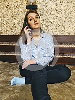 Sad woman sit on bed and talk on smartphone