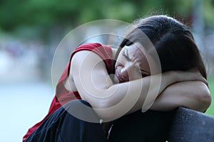 Sad woman in a park complaining on a bench