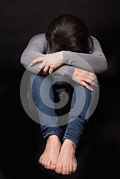 Sad woman sitting on a black background