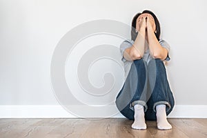 Sad woman sitting on a floor alone in empty room, despair and lonely concept with copy space