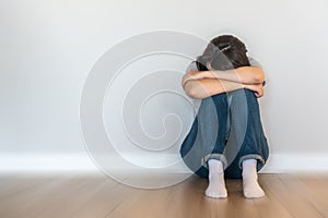 Sad woman sitting on a floor alone in empty room, despair and lonely concept with motion blur effect