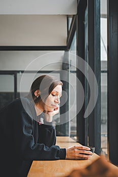 Sad woman sitting by the window looking outside