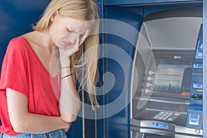 Sad woman standing in front of a ATM bank machine. No money.