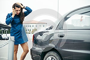 Sad woman standing near car with scratch