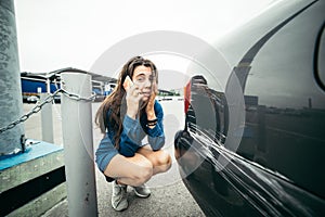 Sad woman standing near car with scratch