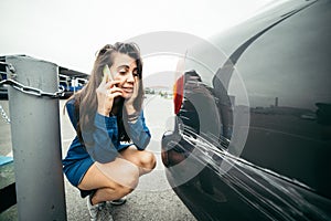 Sad woman standing near car with scratch