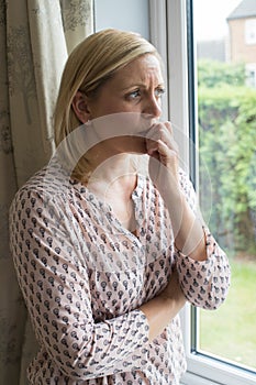 Sad Woman Suffering From Agoraphobia Looking Out Of Window photo