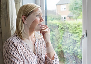 Sad Woman Suffering From Agoraphobia Looking Out Of Window