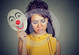 Sad woman taking off clown mask expressing cheerfulness