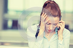 Sad woman talking on mobile phone looking down