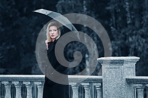 Sad young fashion woman with umbrella walking outdoor