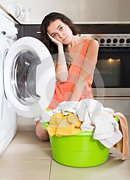 Sad woman using washing machine at home