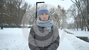 Sad woman walking alone in winter park on snowy day