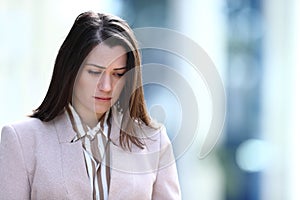 Sad woman walking in the street looking down