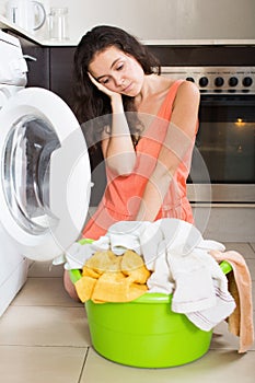 Sad woman washing clothes in machine