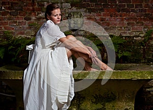 Smutný žena v biely šaty na kameň lavice 