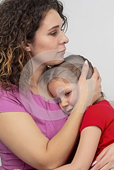 Sad women embraces little frustrated little daughter, girl snuggle to mother