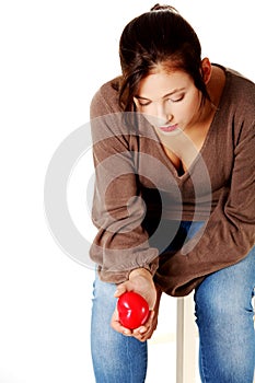 Sad women holding heart in her hand.