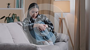 Sad worried asian korean woman having psychological problem sitting on sofa couch feeling alone anxiety depression