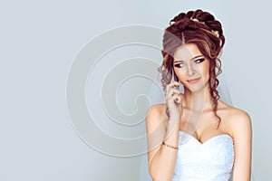 Sad and worried bride talking at mobile phone on light blue background