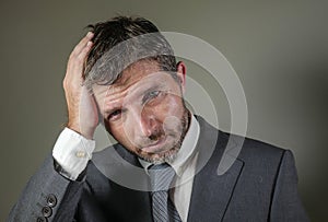 Sad and worried businessman in suit and tie and messy look feeling depressed and stressed in overwhelmed face expression suffering