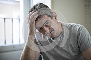 Sad and worried man with grey hair sitting at home couch looking