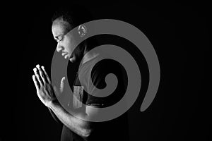 Sad young African man praying in black and white