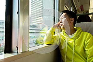 Sad young asian man looking through the window in the train carriage