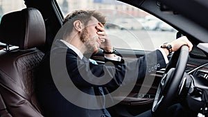 Sad young businessman driving alone in his new car