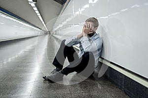 Sad young businessman jobless suffering from depression sitting depressed on ground street subway