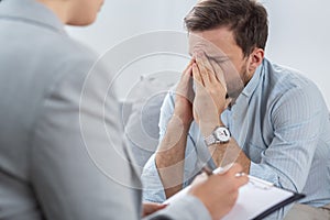 Sad young businessman with problems during session with counselor