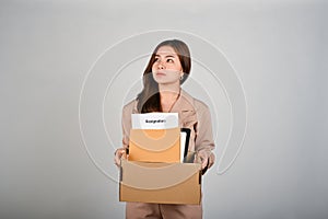Sad young businesswoman holding a box full of her stuff, feeling sad after quitting her job