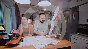 Sad young couple paying the bills. Man and woman sitting in the kitchen and sorting checks and accounts.