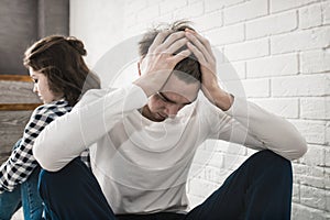 Sad Young couple is sitting back to back on the couch at home having a quarrel