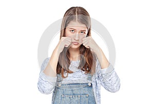 Sad young fashion girl in jeans overalls isolated