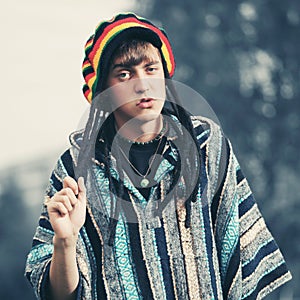 Sad young fashion hipster man in rasta hat and poncho