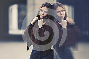 Sad young fashion woman in leather fringe suede jacket leaning on the wall