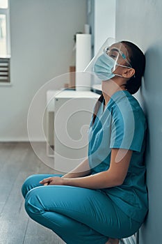 Sad young female nurse in protective workwear photo