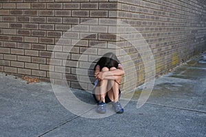 Sad young girl crying outside female toilet building