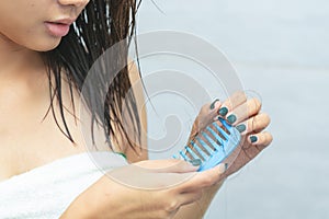 Sad young girl holding her long hair with looking at damaged splitting ends of hair.