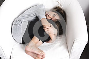 Sad young girl lay on sofa