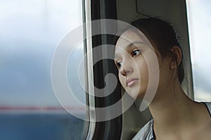 A sad young girl rides a train.