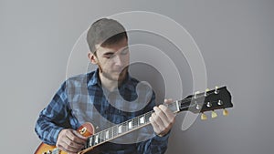 Sad young man with beard holding electric guitar and playing a rock ballad song before rock concert. Music instruments concept