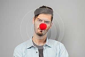 Sad young man with clown nose