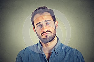 Sad young man on gray wall background