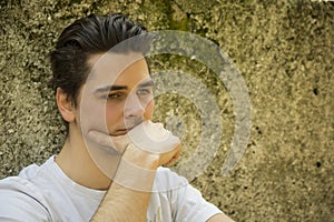 Sad young man with hand on chin thinking