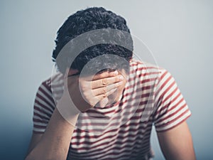 Sad young man with hand on forehead